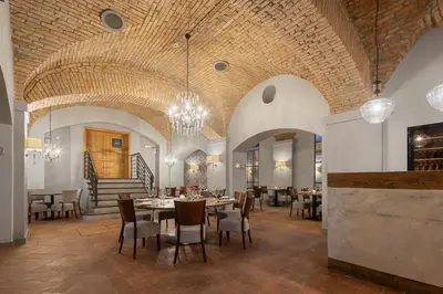 a dining room with tables and chairs and a staircase at Pytloun Chateau Hotel Ctěnice in Prague