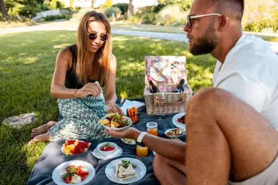 a man and woman sitting on a picnic blanket with food at Pytloun Chateau Hotel Ctěnice in Prague