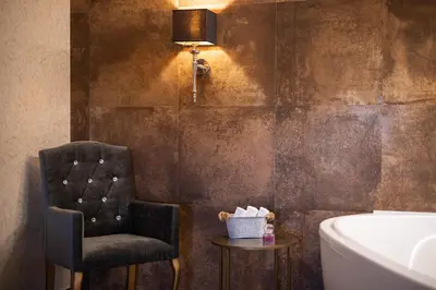 a bathroom with a chair and a sink and a tub at Pytloun Chateau Hotel Ctěnice in Prague