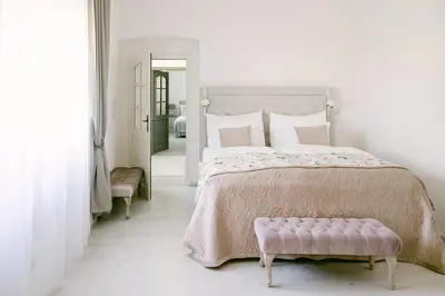a white bedroom with a large bed and a pink bench at Na Kmíně in Obříství