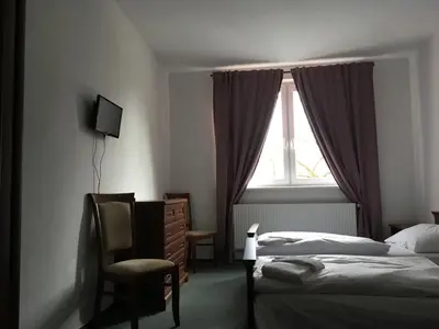 a bedroom with a bed and a chair and a window at Hotel Arko in Prague