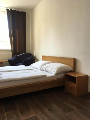 a bedroom with a bed and a chair and a window at Hotel Arko in Prague
