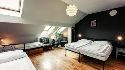 a bedroom with two beds and a table and a chandelier at Sir Toby's Hostel in Prague