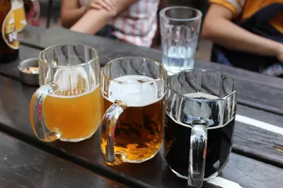 three glasses of beer sitting on a wooden table at Sir Toby's Hostel in Prague
