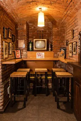 a bar with wooden stools and a tv on a brick wall at Sir Toby's Hostel in Prague