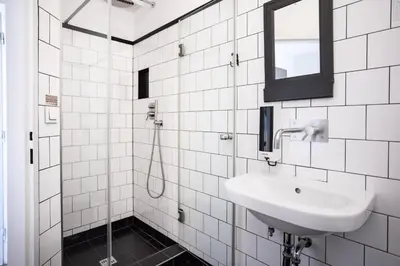 a white tiled bathroom with a sink and a mirror at Sir Toby's Hostel in Prague