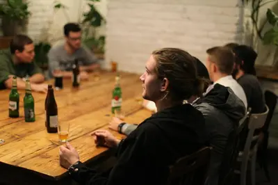a group of people sitting around a table with wine bottles at Sophie's Hostel in Prague