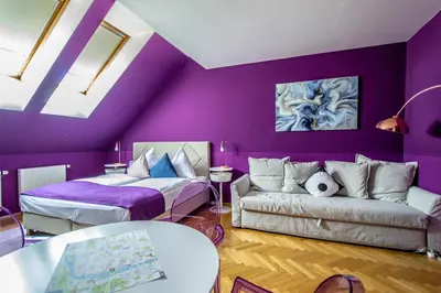 a purple living room with a couch and a bed at Garden Apartments in Prague