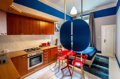 a kitchen with two red chairs and a blue table at Garden Apartments in Prague