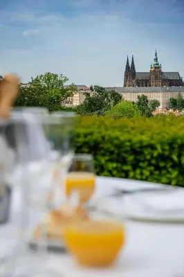 a table with plates of food and a view of a castle at Nebozizek Hotel a Restaurant in Prague