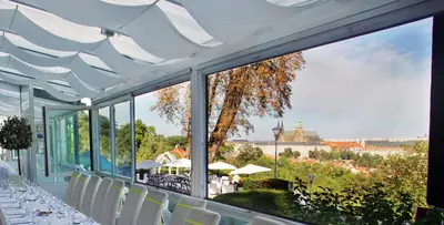 a table with white chairs and a view of the city at Nebozizek Hotel a Restaurant in Prague