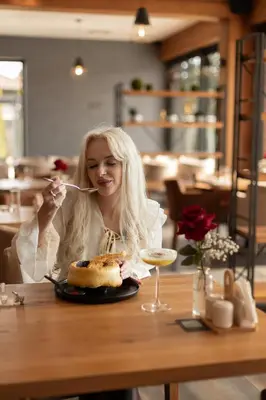 a woman sitting at a table eating a plate of food at GAZDA Hotel&Restaurant - Self Chek-In in Jesenice