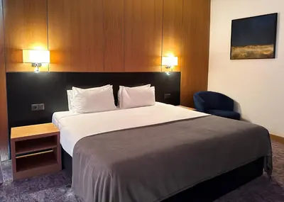a hotel room with a large bed and a chair at GAZDA Hotel&Restaurant - Self Chek-In in Jesenice