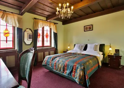 a bedroom with a bed and a chandelier and windows at U Páva in Prague