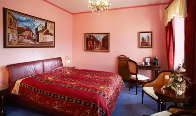 a bedroom with a red bed and a table and chairs at U Páva in Prague