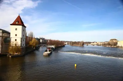 a river with a building and a boat in the water at Quiet apartment in the city center with own terrace in Prague