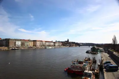 a river with boats docked in a city with buildings at Quiet apartment in the city center with own terrace in Prague