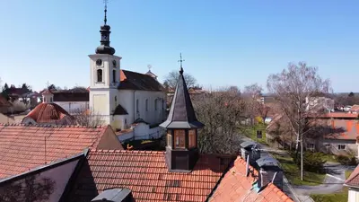 a church with a steeple on top of roofs at Penzion u Svatého Prokopa in Středokluky