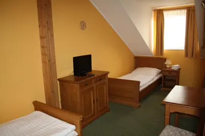 a bedroom with two beds and a tv on a dresser at Hotel Bouček in Mochov
