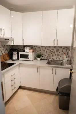a kitchen with white cabinets and a sink and a microwave at Central 3bdr penthouse with terrace&AC in Prague