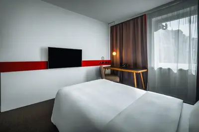 a hotel room with a white bed and a tv at Hotel PULSE8 in Prague