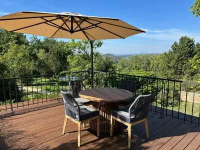a wooden deck with a table and chairs and an umbrella at Vikendovka Korce in Dubá