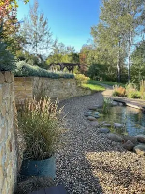 a garden with a stone wall and a pond at Vikendovka Korce in Dubá