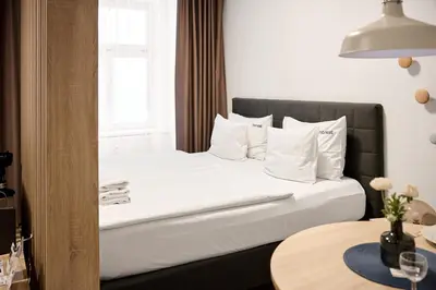 a bedroom with a bed with white pillows and a table at HONEST Smichov in Prague