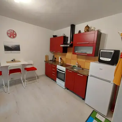 a kitchen with red cabinets and a table and a microwave at Garsonka in Jílové u Prahy