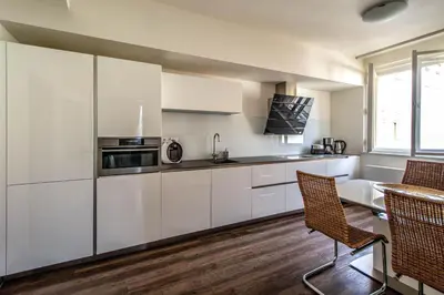 a kitchen with white cabinets and a table and chairs at Unique Charles Bridge 2BDR Apartment. in Prague