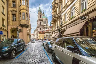 a city street with cars parked on a cobblestone street at Unique Charles Bridge 2BDR Apartment. in Prague