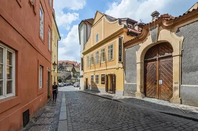 a person walking down a cobblestone street with buildings at COZY QUIET STUDIO AT CHARLES BRIDGE in Prague