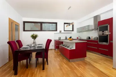 a kitchen with red cabinets and a table with chairs at Prague Days - Two-bedroom Family Apartment with Terrace and Garage in Vinohrady in Prague