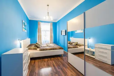 a blue bedroom with two beds and a mirror at Apartman Exclusive Prague in Prague