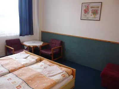 a room with two beds and a table and chairs at Hotel Hasa in Prague