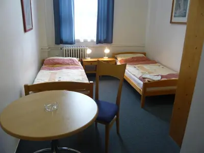 a room with two beds and a table and chairs at Hotel Hasa in Prague