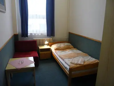 a small bedroom with a bed and a chair at Hotel Hasa in Prague