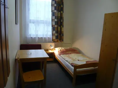 a small room with a bed and a table and a window at Hotel Hasa in Prague