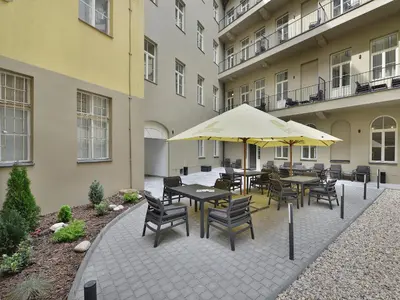 an outdoor patio with tables and chairs and an umbrella at EA Hotel New Town in Prague