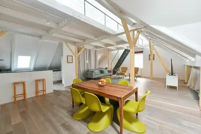 a living room with a wooden table and yellow chairs at Our Loft at Charles Bridge in Prague