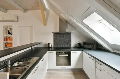 an attic kitchen with white cabinets and a window at Our Loft at Charles Bridge in Prague