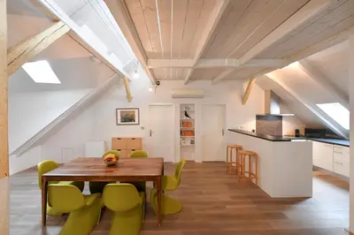 a kitchen and dining room with a wooden table and green chairs at Our Loft at Charles Bridge in Prague