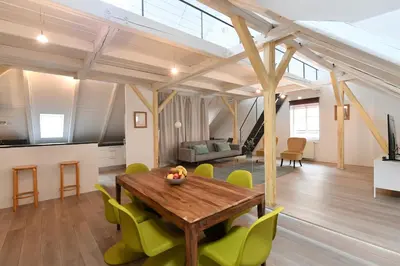 a living room with a wooden table and green chairs at Our Loft at Charles Bridge in Prague