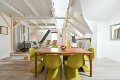 a dining room with a wooden table and green chairs at Our Loft at Charles Bridge in Prague