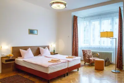 a bedroom with a bed and a chair and a window at Pension Karnet in Prague