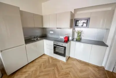 a small kitchen with white cabinets and a wooden floor at Letna Garden Suites in Prague