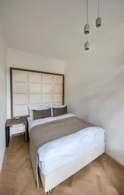 a white bedroom with a large bed and a wooden floor at Letna Garden Suites in Prague