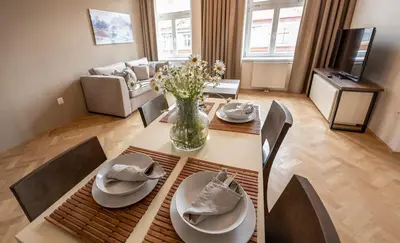 a living room with a dining room table with a vase of flowers at Letna Garden Suites in Prague