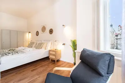 a white bedroom with a bed and a chair at Celine Prague Hostel in Prague