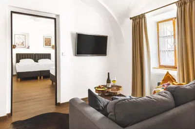 a living room with a couch and a tv on a wall at Hotel Baroko in Prague